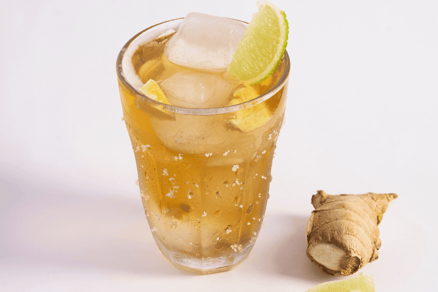 Ginger cocktail with ice, lime, and fresh ginger on a white background.