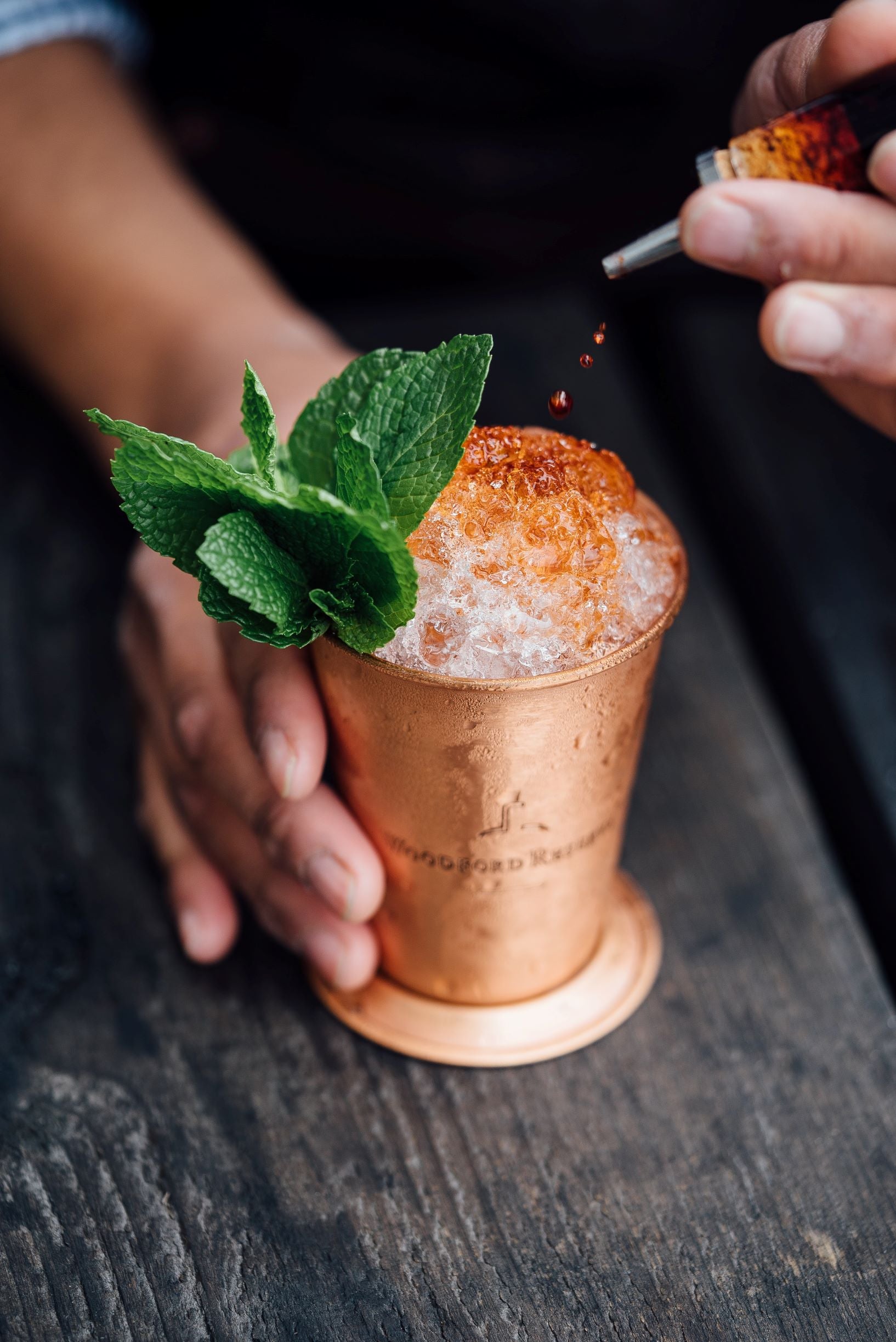 a bartender adds the finishing touch --- bitters --- to a cocktail