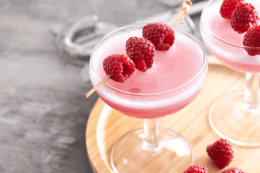 French Martini cocktails garnished with fresh raspberries on skewers.