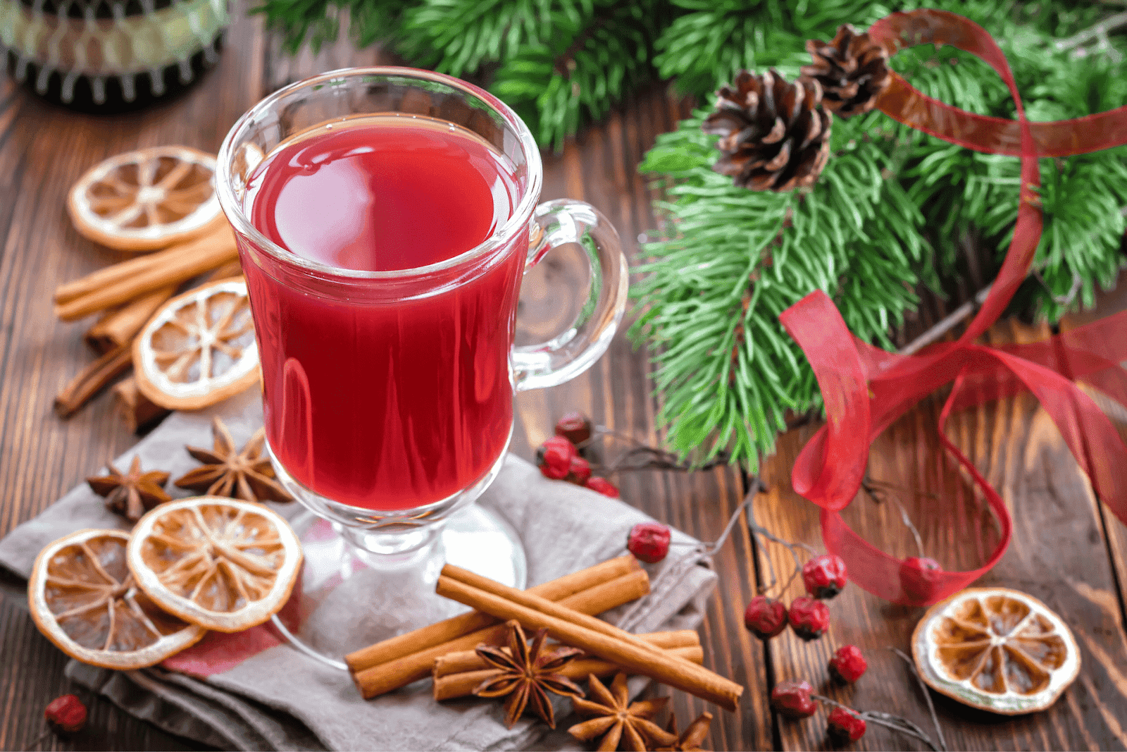 Glass of Christmas punch drink with cinnamon sticks and festive decorations
