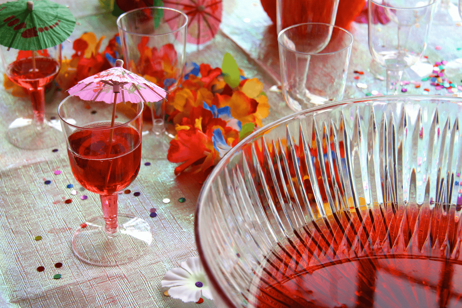 Colorful party setup with glasses of red punch and decorative umbrellas