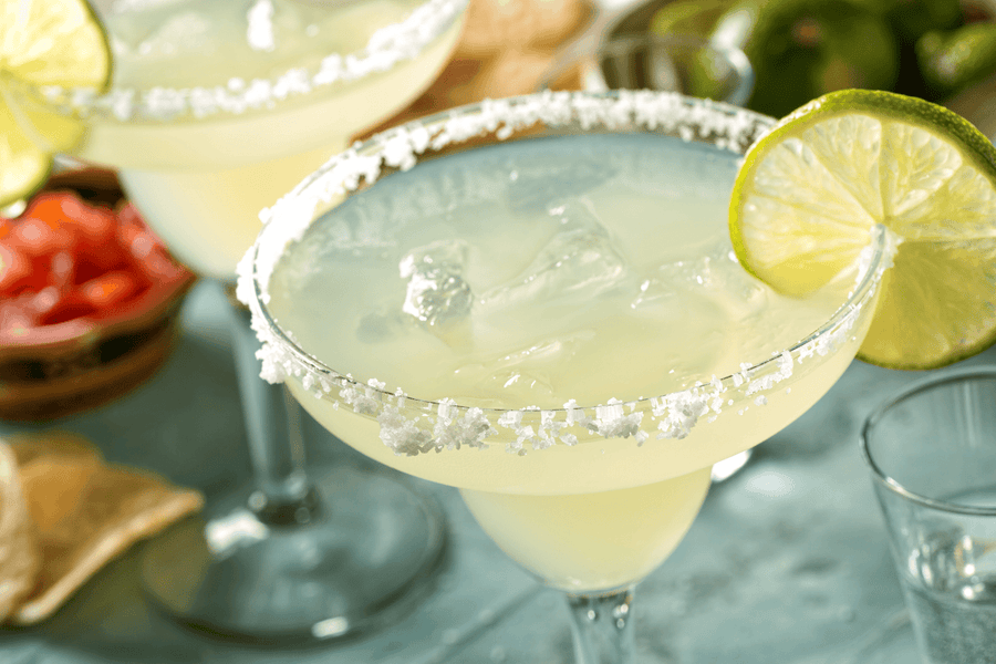 Classic margaritas with salt rims and lime slices on a table.