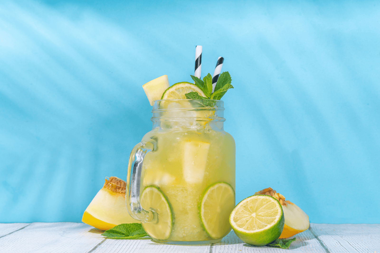 Mojito Mocktail with lime, mint, and melon in a mason jar against a blue background.