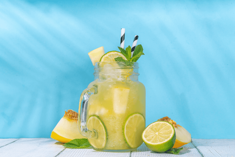 Mojito Mocktail with lime, mint, and melon in a mason jar against a blue background.