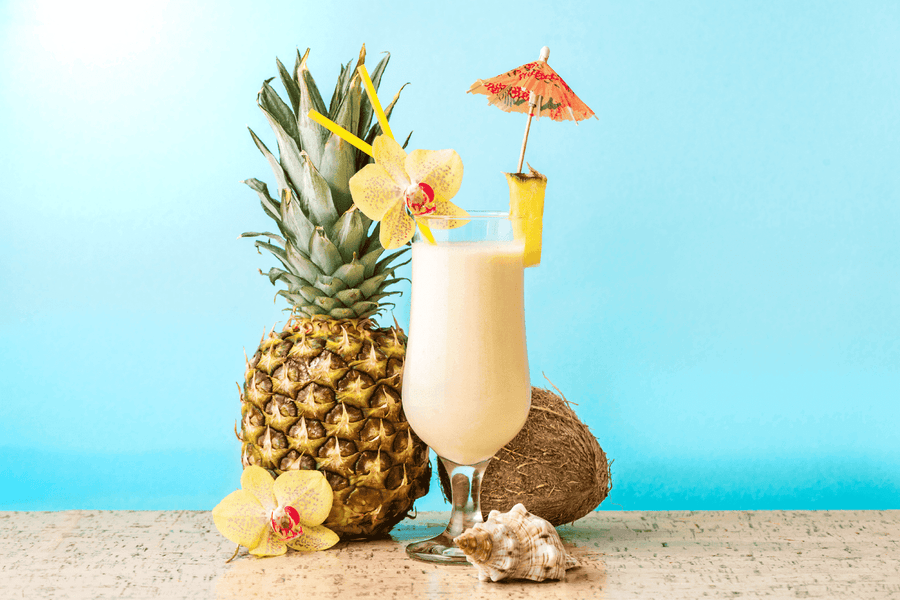Tropical pina colada with pineapple, coconut, and a cocktail umbrella on a blue background.
